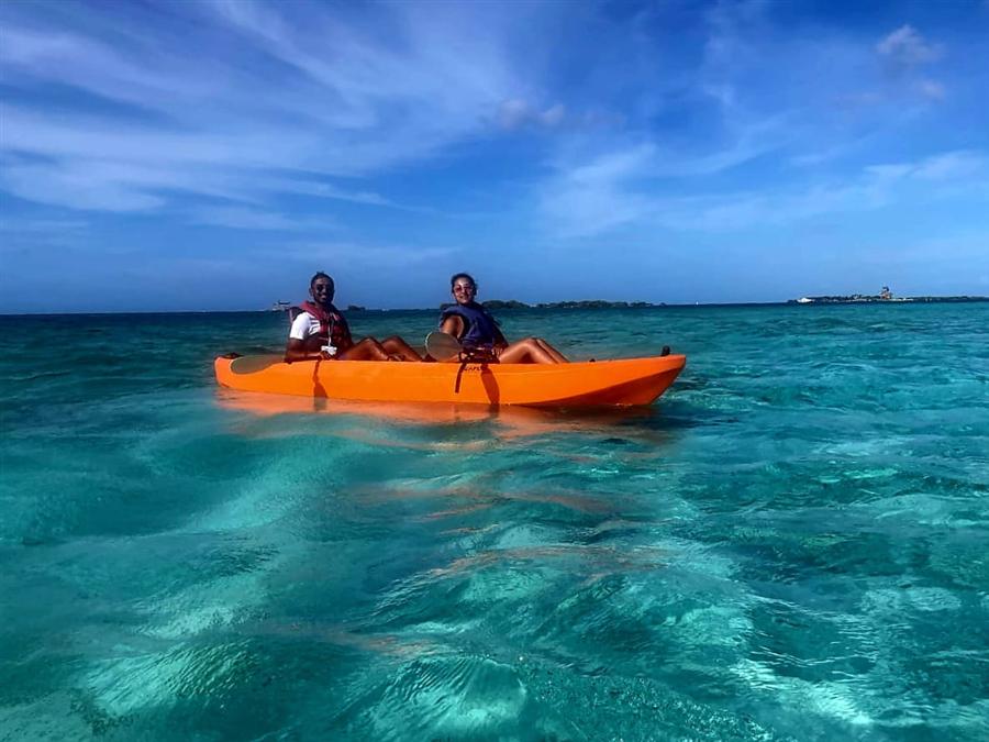Two guests in an orange kayak on bright turquoise water